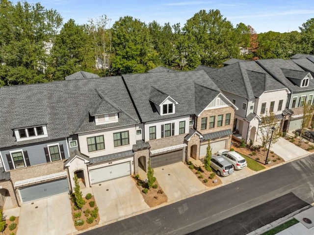 exterior space featuring a garage, a residential view, roof with shingles, and driveway