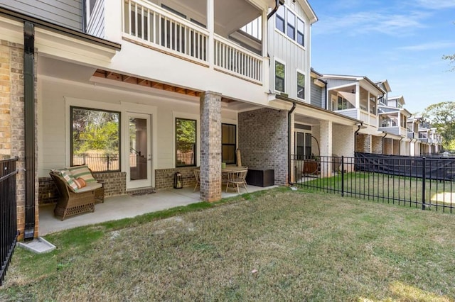 back of property featuring brick siding, a lawn, a patio area, fence, and a residential view