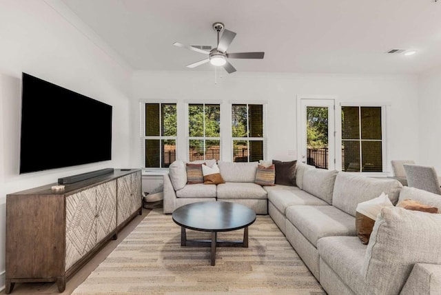 living room with ornamental molding, visible vents, ceiling fan, and light wood finished floors