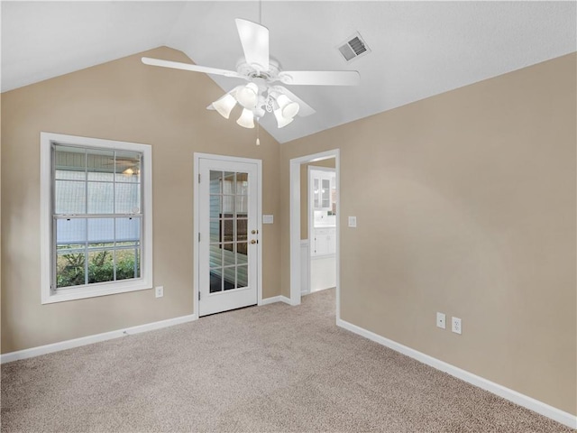 spare room with lofted ceiling, ceiling fan, light colored carpet, visible vents, and baseboards