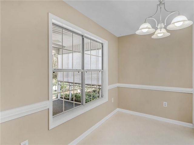 spare room featuring baseboards and a notable chandelier