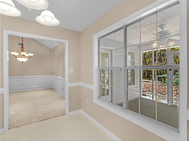 doorway to outside featuring a notable chandelier, wainscoting, carpet, and a decorative wall