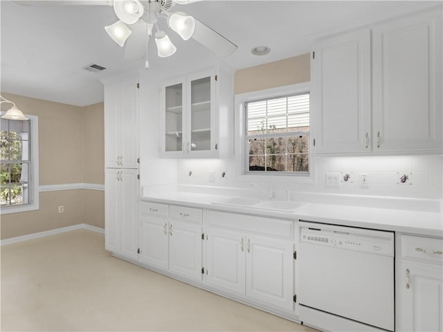 kitchen featuring light countertops, glass insert cabinets, white cabinetry, a sink, and dishwasher