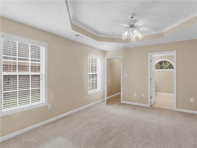 unfurnished bedroom featuring light carpet, a textured ceiling, a raised ceiling, and visible vents