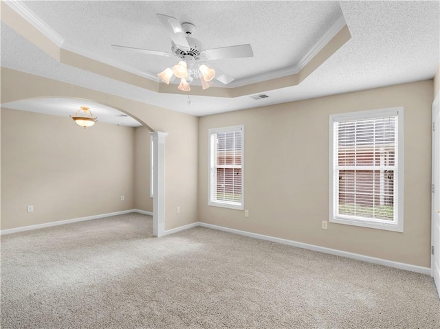 spare room with arched walkways, light carpet, visible vents, baseboards, and a raised ceiling