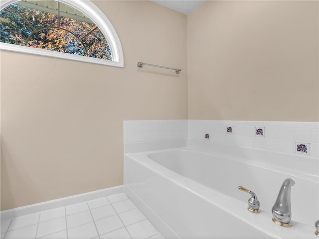 full bath featuring tile patterned flooring, a bath, and baseboards