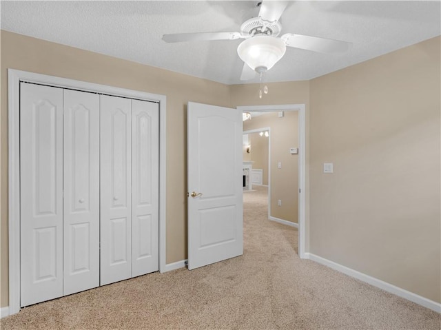 unfurnished bedroom with a ceiling fan, a closet, light carpet, and baseboards