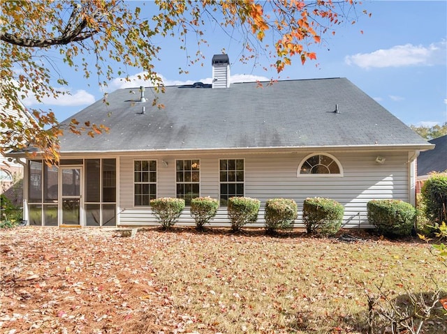 back of property with a sunroom and a chimney