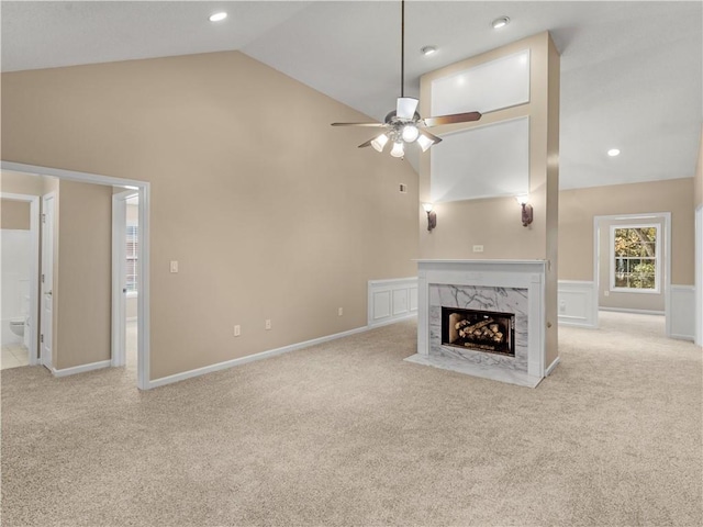 unfurnished living room featuring light carpet, ceiling fan, high vaulted ceiling, and a high end fireplace