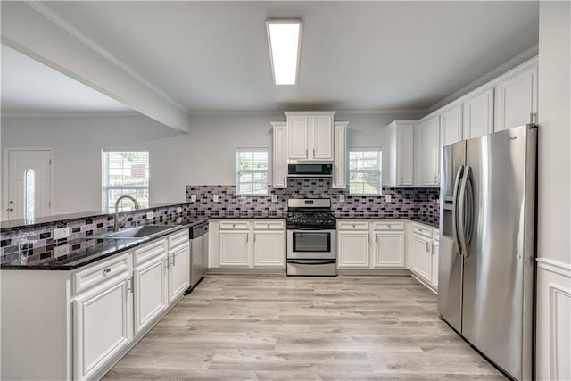 kitchen featuring backsplash, appliances with stainless steel finishes, a peninsula, and a sink