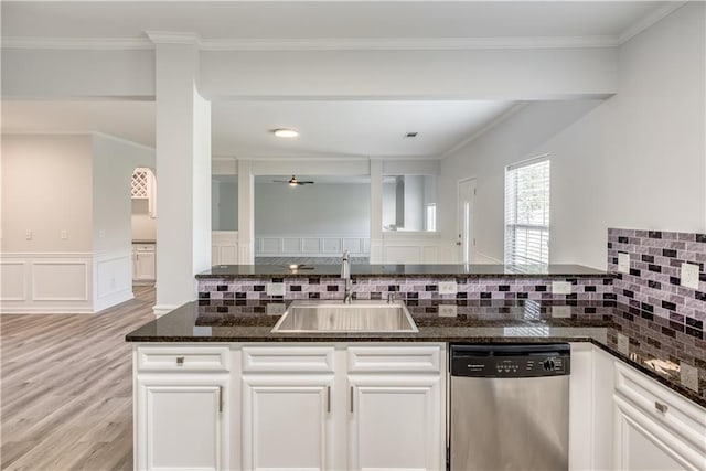 kitchen featuring dark stone countertops, light wood-style flooring, stainless steel dishwasher, white cabinetry, and a sink