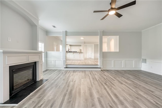 unfurnished living room with a glass covered fireplace, visible vents, and light wood-type flooring