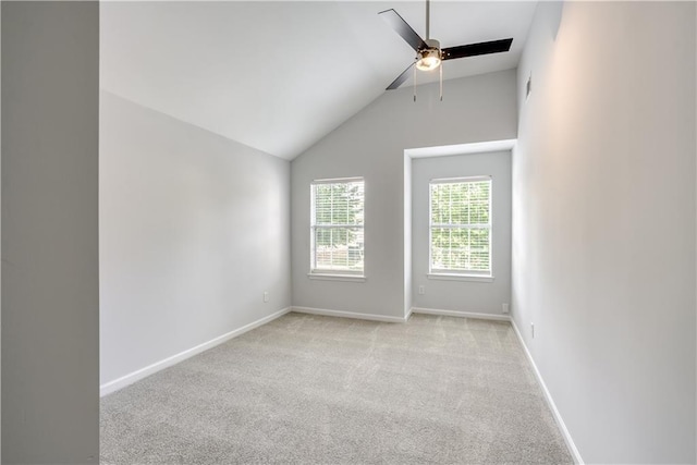 spare room featuring light colored carpet, lofted ceiling, baseboards, and ceiling fan