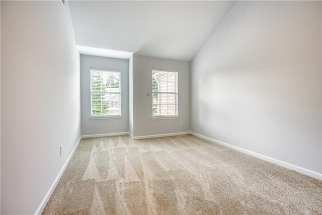 unfurnished room featuring light colored carpet, baseboards, and vaulted ceiling