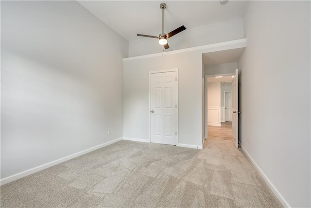 unfurnished bedroom featuring baseboards, light colored carpet, and a ceiling fan