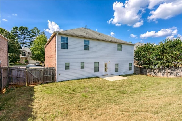 back of house featuring a patio, a lawn, brick siding, and a fenced backyard