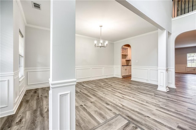 unfurnished dining area with arched walkways, visible vents, a chandelier, and ornate columns