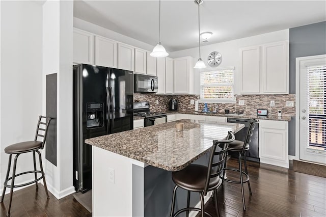 kitchen featuring black appliances, hanging light fixtures, a kitchen island, and white cabinetry