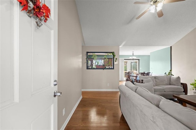 living room with ceiling fan with notable chandelier and dark hardwood / wood-style floors