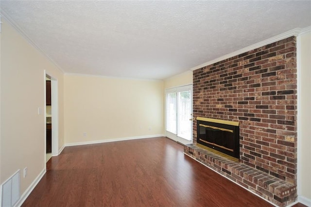 unfurnished living room with dark hardwood / wood-style flooring, a brick fireplace, ornamental molding, and a textured ceiling