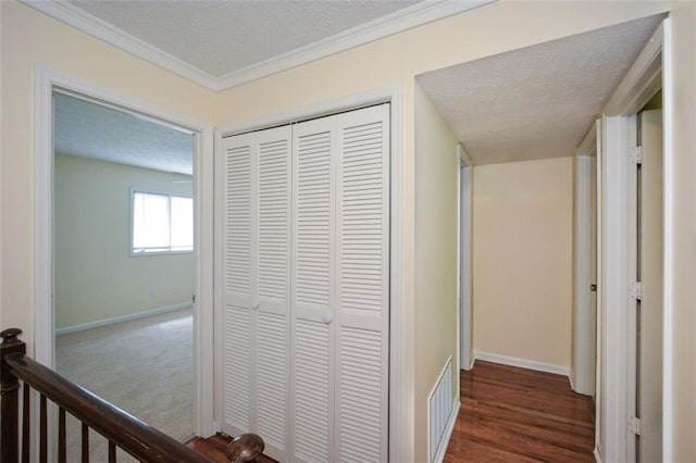 hallway with dark hardwood / wood-style flooring, ornamental molding, and a textured ceiling