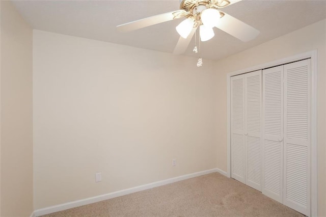 unfurnished bedroom featuring ceiling fan, light colored carpet, and a closet