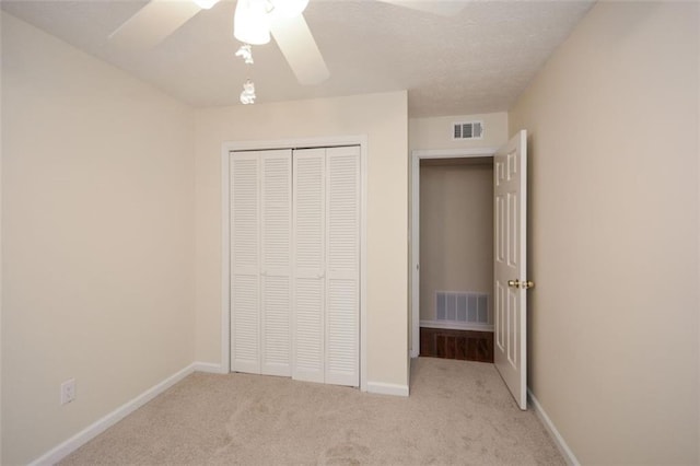 unfurnished bedroom featuring light carpet, a closet, and ceiling fan