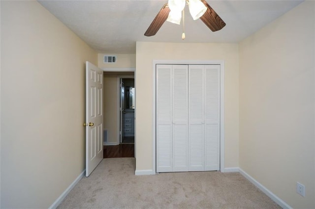 unfurnished bedroom featuring light colored carpet, a closet, and ceiling fan