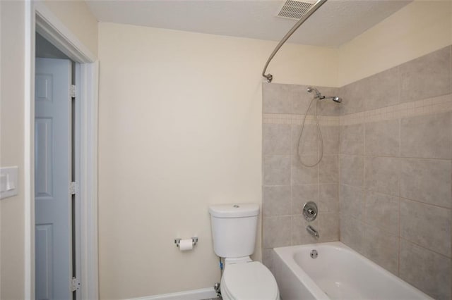 bathroom with tiled shower / bath combo and toilet