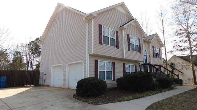 view of property exterior with concrete driveway, an attached garage, and fence