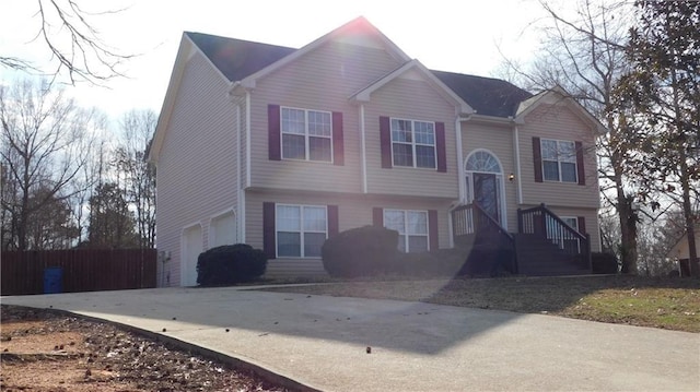 raised ranch featuring driveway, a garage, and fence