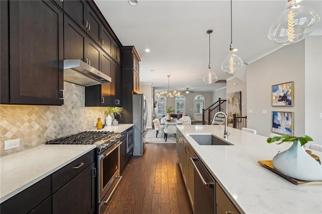 kitchen featuring dark wood-type flooring, sink, light stone counters, hanging light fixtures, and stainless steel appliances