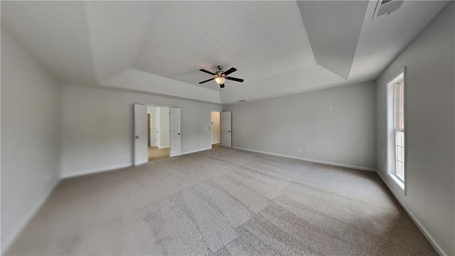 unfurnished bedroom featuring a raised ceiling, multiple windows, and baseboards