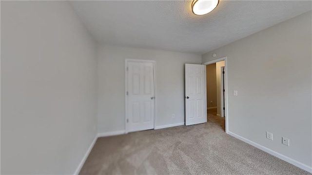 unfurnished bedroom featuring baseboards, carpet floors, and a textured ceiling