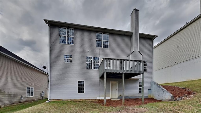 rear view of property with a wooden deck, a lawn, and a chimney