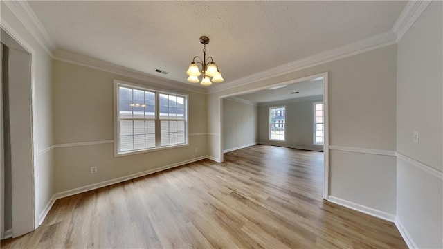 spare room with visible vents, an inviting chandelier, light wood-style flooring, and crown molding