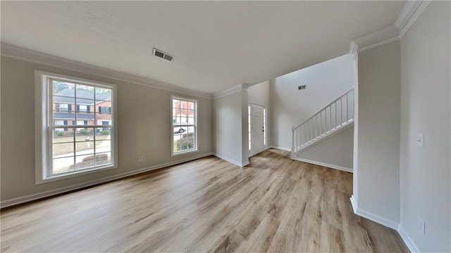 interior space with visible vents, light wood-style flooring, baseboards, and ornamental molding