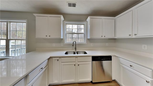 kitchen with visible vents, a sink, light countertops, white cabinets, and stainless steel dishwasher