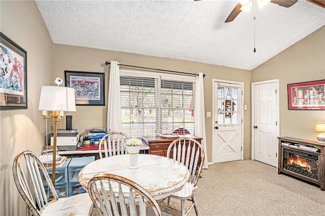 dining space featuring a ceiling fan, light carpet, a textured ceiling, and vaulted ceiling