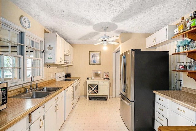 kitchen with a ceiling fan, light floors, a sink, stainless steel appliances, and white cabinets