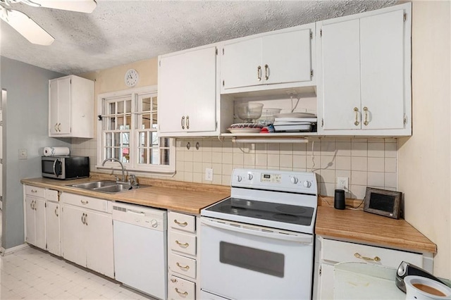 kitchen featuring a textured ceiling, white appliances, a sink, light countertops, and tasteful backsplash