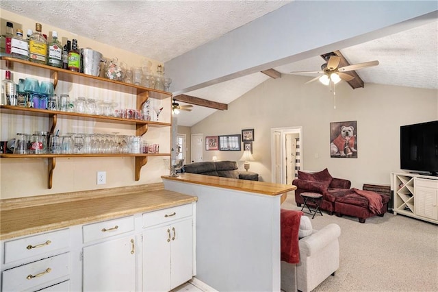 kitchen featuring ceiling fan, a textured ceiling, open floor plan, and vaulted ceiling with beams
