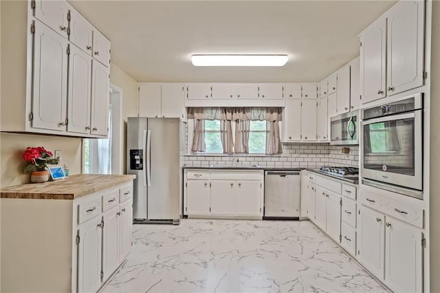 4025 Cheoah Dr, Douglasville, GA 30135 - kitchen featuring stainless steel appliances, light marble finish floors, a sink, tasteful backsplash, and white cabinetry