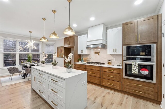 kitchen with stainless steel appliances, white cabinets, custom range hood, backsplash, and pendant lighting