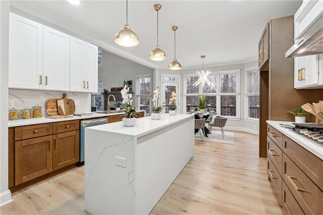 kitchen featuring appliances with stainless steel finishes, wall chimney range hood, white cabinets, and pendant lighting