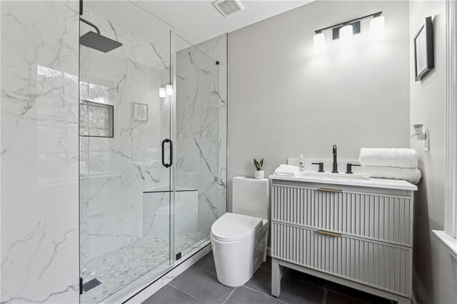 full bath with a marble finish shower, visible vents, toilet, vanity, and tile patterned flooring