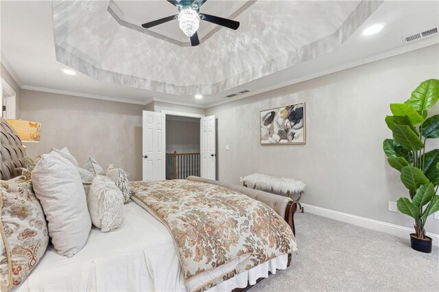 carpeted bedroom with baseboards, visible vents, a raised ceiling, and crown molding