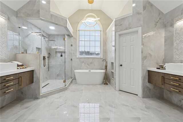 bathroom featuring vaulted ceiling, marble finish floor, a stall shower, and tile walls