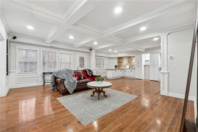 living room featuring beamed ceiling, coffered ceiling, wood finished floors, and decorative columns