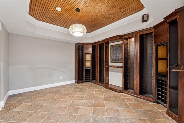 unfurnished room featuring wood ceiling, a tray ceiling, and baseboards